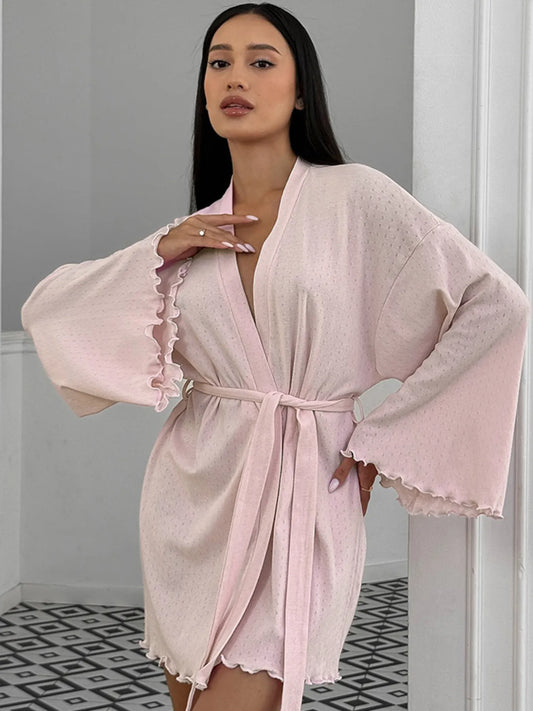 Woman in light pink belted robe with ruffle sleeves, loungewear fashion style