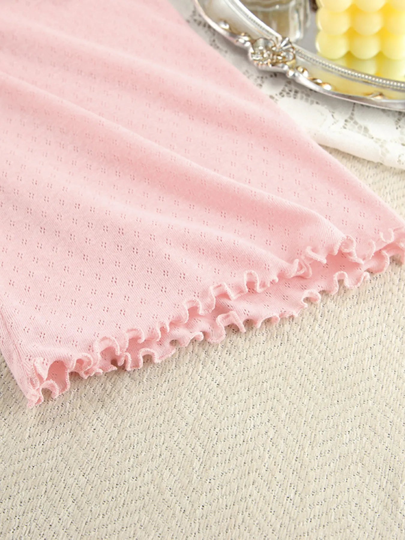 Pink ribbed lounge wear fabric with ruffled edge detail on textured background