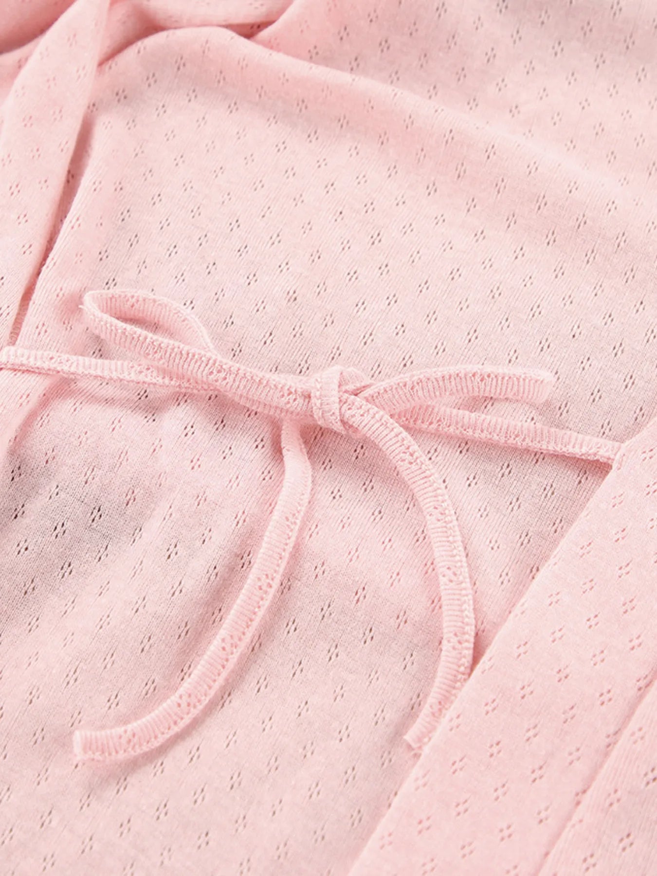 Soft pink loungewear fabric with delicate bow tie and subtle textured pattern