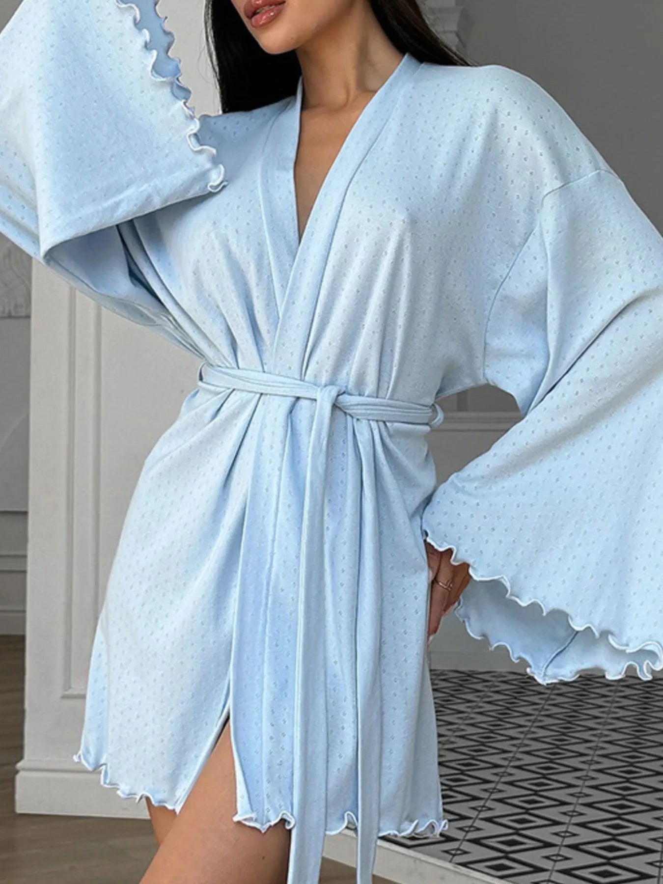 Woman wearing light blue belted kimono robe with textured fabric and flared sleeves